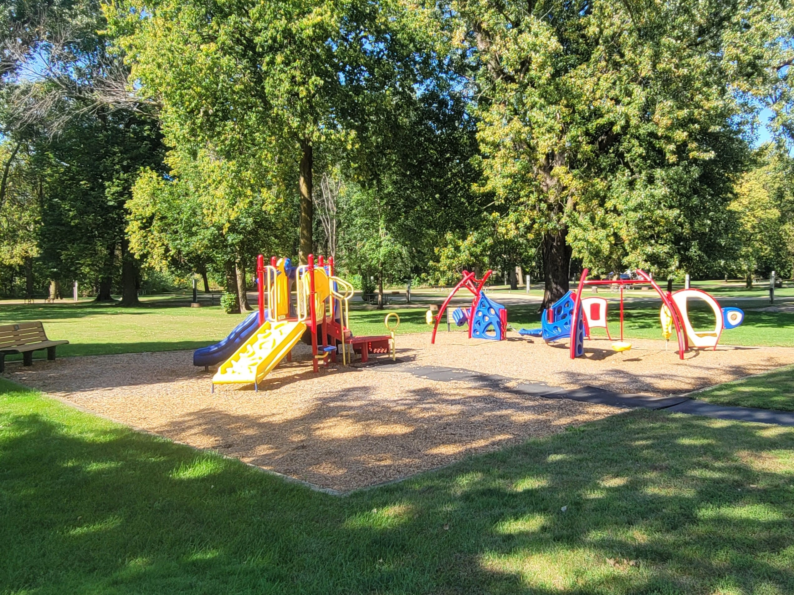 Playground with climbing frames with green grass and trees