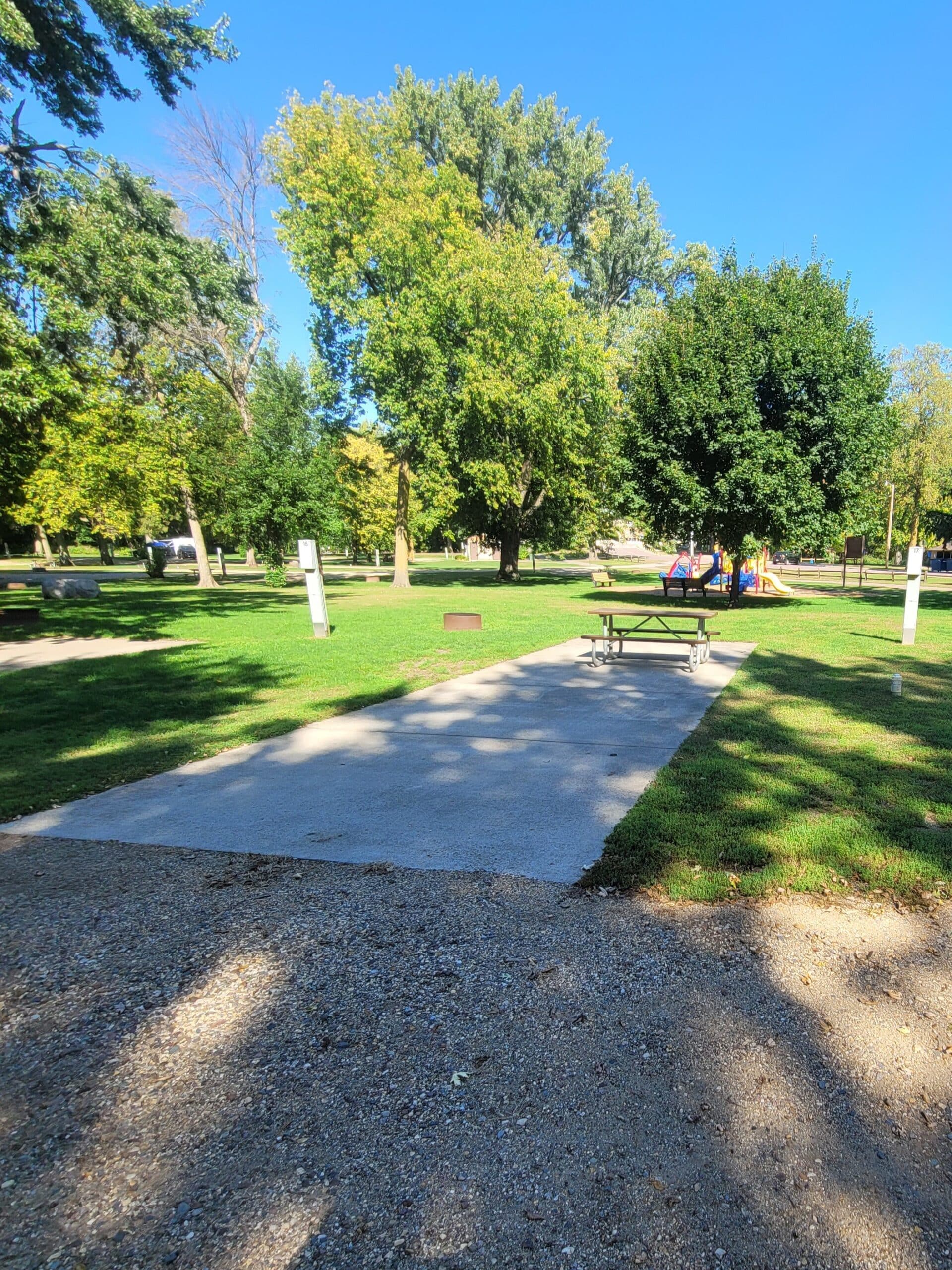 campground site campground site 15 with a gravel path, trees, green grass and a picnic table