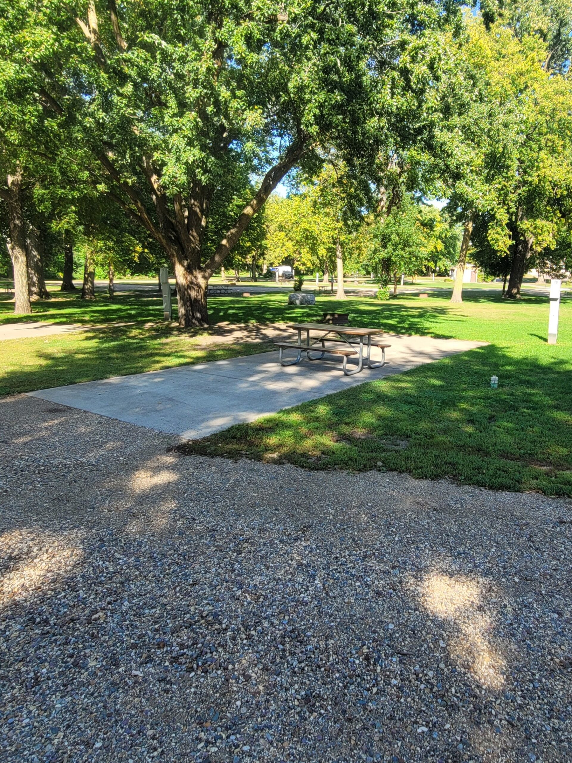 campground site campground site 18 with a gravel path, trees, green grass and a picnic table