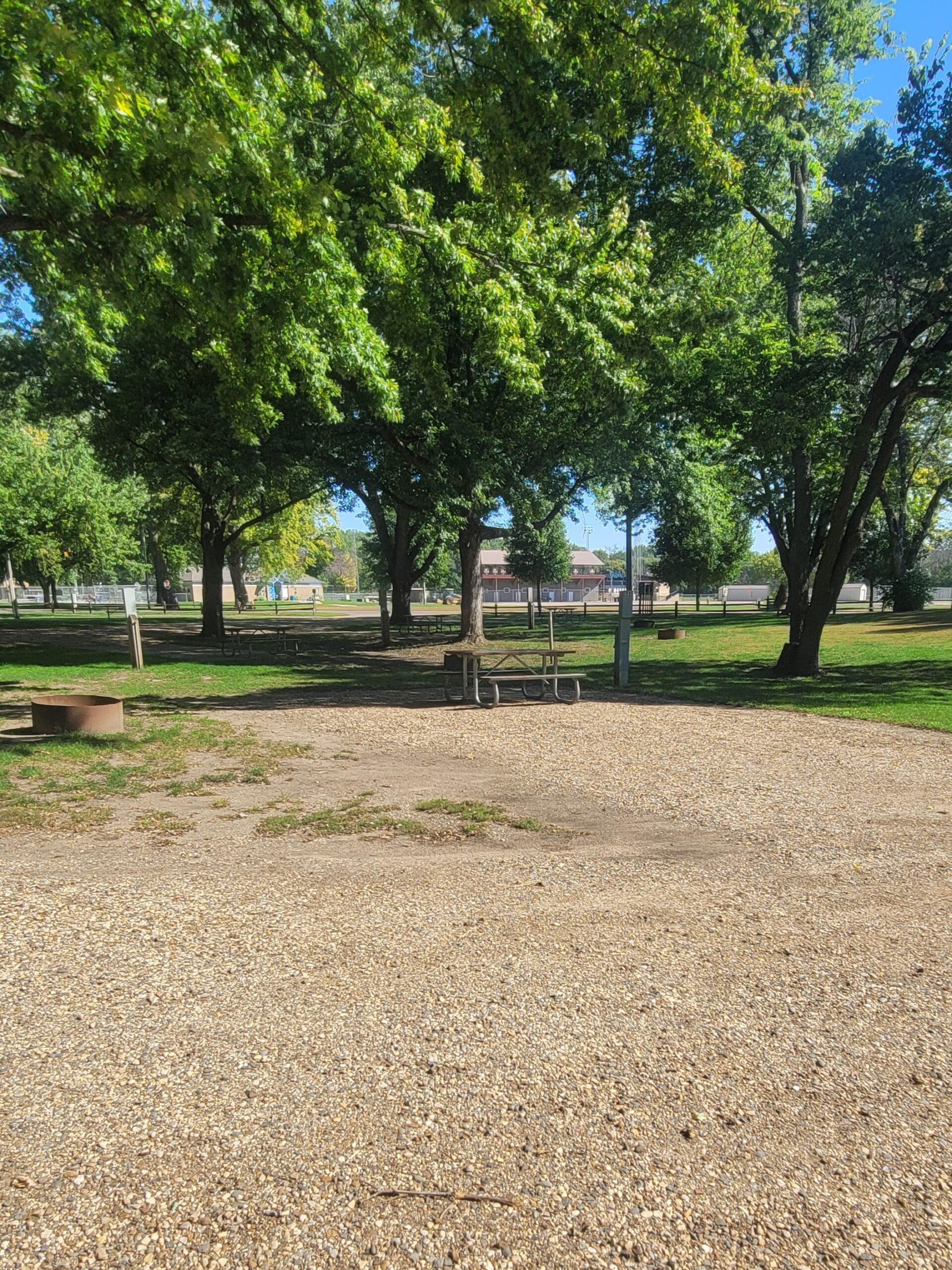 campground site 32 with a wide gravel path, trees and green grass with a picnic table