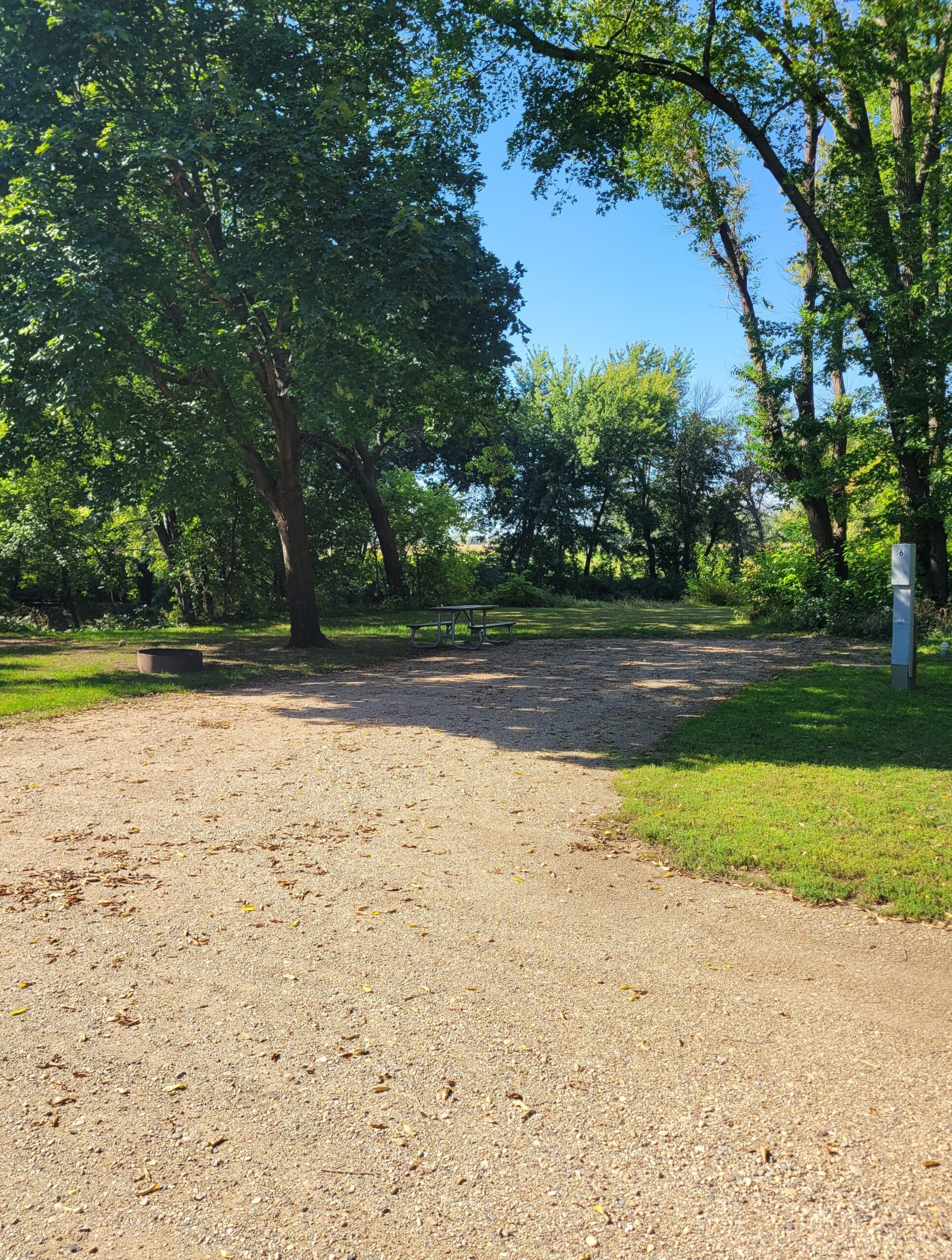 campground site 6 with a gravel path, trees and green grass