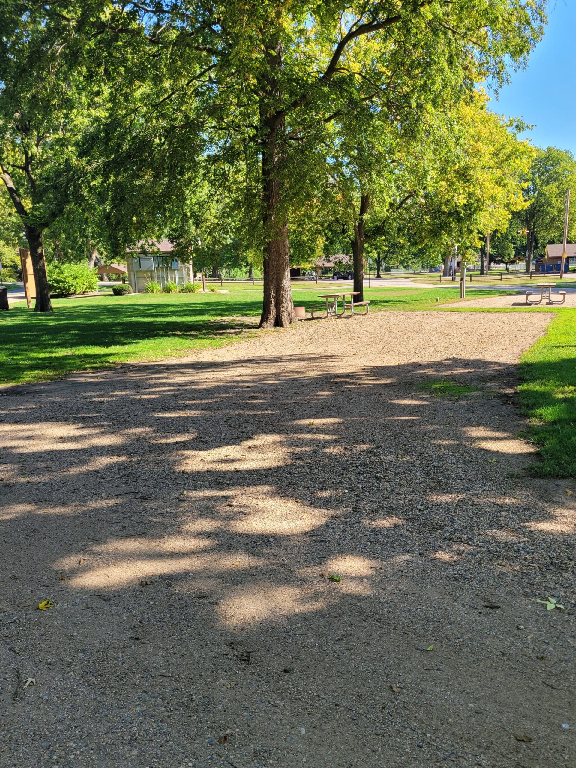 campground site 9 with a gravel path, trees, green grass and picnic tables